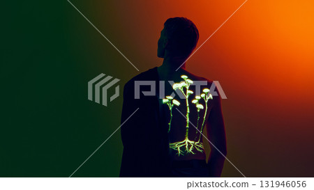 Man with neon botanical projection on back in orange and green gradient lighting 131946056