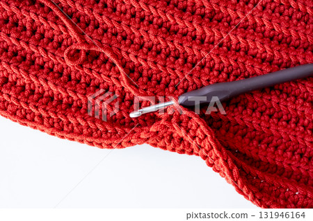 Close up of red crochet fabric with hook for knitting enthusiasts Close up of red crochet fabric with hook for knitting enthusiasts 131946164
