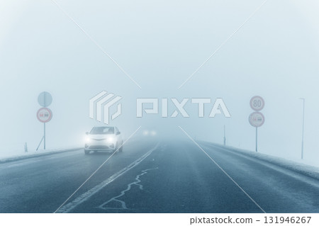Scenic view nature park highway slippery mountain alpine fog road driving cars moving fast speed motion. Snowfall danger blizzard bad winter weather conditions. Cold snowy day snowstorm background 131946267