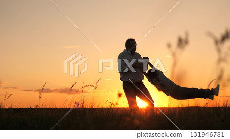 Silhouette father tossing and spinning child, sunset sky and sun, parent with daughter outdoors, man holding small hands, people playing in nature, little kid flying, childhood dream moments, together 131946781