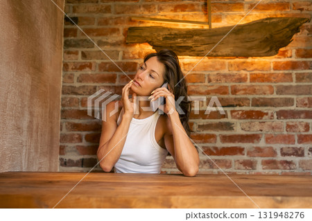 A reflective and thoughtful woman enjoys a warm phone conversation in a cozy, rustic environment, surrounded by charm 131948276