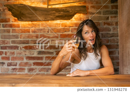 A joyful woman savoring a delightful glass of wine, radiating happiness in an elegantly designed rustic bar setting A joyful woman savoring a delightful glass of wine, radiating happiness in an elegantly designed rustic bar setting 131948278