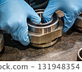 Hands assembling metal components in a workshop with focus on precision and craftsmanship 131948354