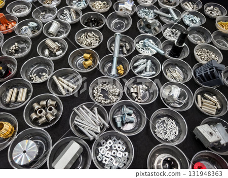 Variety of mechanical components organized in clear containers on a black surface for easy identification and access 131948363