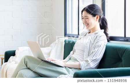 坐在沙發上使用電腦的女人 131948936