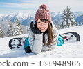 A smiling snowboarding woman lying on the snow 131948965