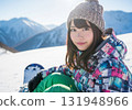 A woman in colorful snowboard wear smiling in the sunshine on a snowy mountain 131948966