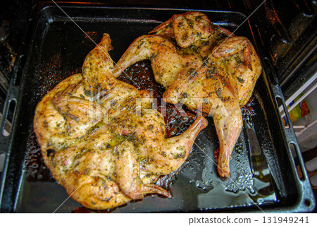 Chicken roasting in oven. Two tobacco chickens on a baking sheet in the oven. Chicken roasting in oven. Two tobacco chickens on a baking sheet in the oven. 131949241