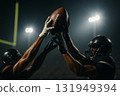 American football players reaching for ball under stadium lights, action concept 131949394