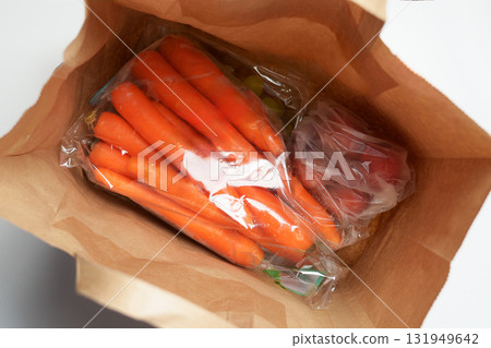 Supermarket paper bag with purchased fresh vegetables and fruits. Carrots, red bell peppers, green grapes 131949642