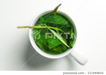 Brewing mint sprigs with leaves and stems in ceramic mug on white table. Healthy healing drink 131949643