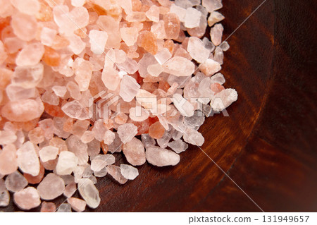 A pile of coarse Himalayan salt on a brown wooden surface. Macro shot. 131949657