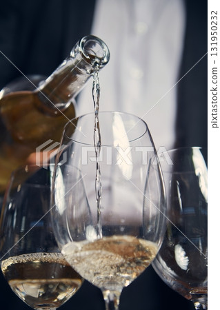 Close up of white wine flowing into glass during tasting ceremony Close up of white wine flowing into glass during tasting ceremony 131950232