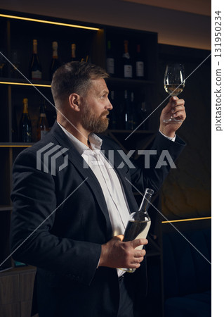 Sommelier examining clarity of white wine under warm light Sommelier examining clarity of white wine under warm light 131950234
