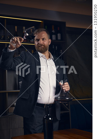 Sommelier evaluating wine color and clarity under soft light Sommelier evaluating wine color and clarity under soft light 131950250