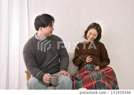 一對年輕夫婦在沙發上休息，孕婦 131950346