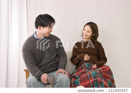 一對年輕夫婦在沙發上休息，孕婦 131950347