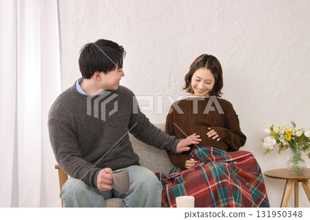 一對年輕夫婦在沙發上休息，孕婦 131950348