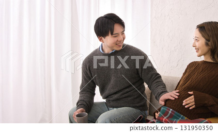 A young couple relaxing on the sofa, pregnant woman 131950350