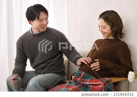 一對年輕夫婦在沙發上休息，孕婦 131950352