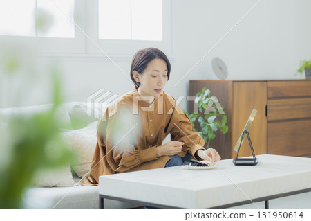 A woman looking in the mirror in the living room A woman looking in the mirror in the living room 131950614