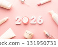 Best skincare products and cosmetic trends of 2026 concept. 2026 white number with lip balm, cream bottle, serum and lotion on pink background. 131950731