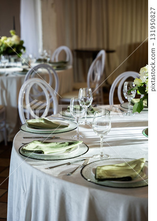 Elegant wedding banquet hall table setting with floral centerpiece and glassware 131950827