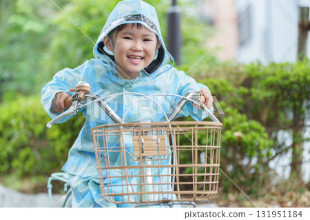下雨天,一個穿著雨衣騎自行車的孩子 下雨天,一個穿著雨衣騎自行車的孩子 131951184