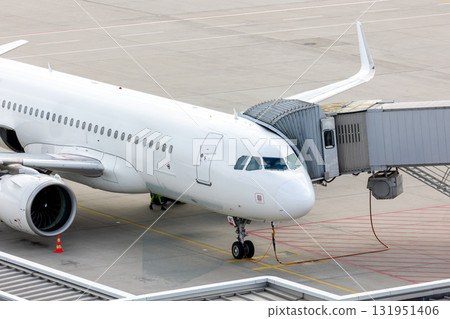 modern regional passenger airplane connected to jet bridge airport terminal boarding ground operations. Modern jet stands on tarmac ready for next flight, symbolizing global travel and transportation 131951406