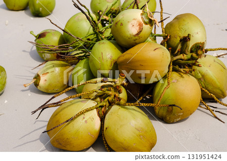 Fresh green coconuts gathered on a sunny day at a tropical location, showcasing their natural beauty and potential for refreshing drinks and culinary uses 131951424