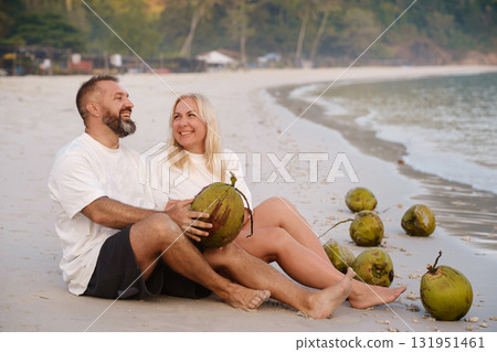 A cheerful couple enjoys a relaxed morning on the beach with coconuts in the background on Redang Island. Malaysia 131951461