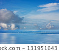 Scenic view of wind turbines on calm ocean under blue sky with clouds 131951643
