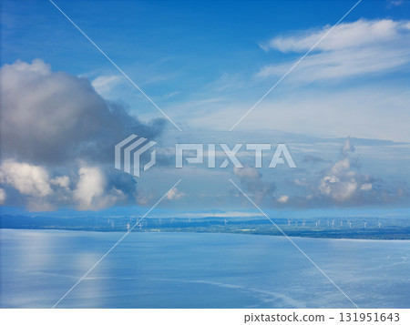 Scenic view of wind turbines on calm ocean under blue sky with clouds 131951643