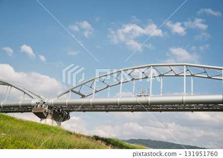 Aqueduct and water pipe bridge spanning the levee seen from the riverbank 131951760