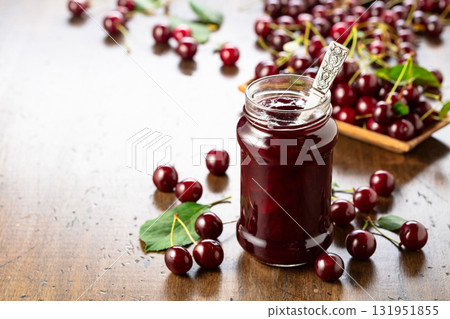 Cherry jam and fresh berries on an old wooden table. Cherry jam and fresh berries on an old wooden table. 131951855