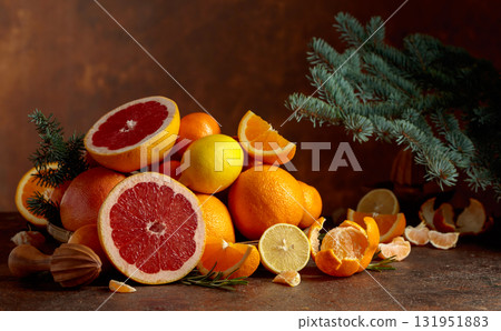Citrus fruits and branch of spruce on a brown background. 131951883