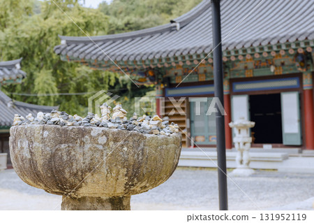 A pile of stones, used to make wishes, is placed on a stone table at Jangansa Temple in Gijang, Busan, South Korea. Landscape. 131952119