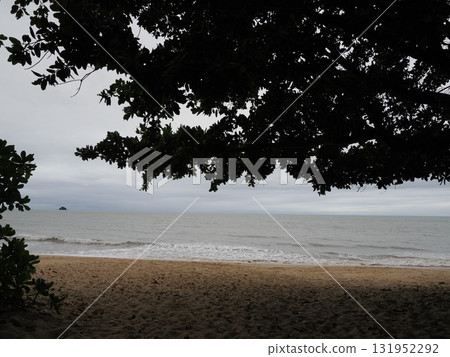 Palm Cove Beach – Cloudy sea and island silhouettes seen from the shade of a tree Palm Cove Beach – Cloudy sea and island silhouettes seen from the shade of a tree 131952292