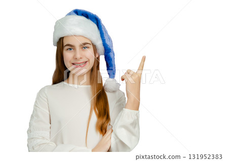 Smiling girl with blue Santa hat on white background. Festive portrait for Christmas and winter celebrations. Smiling girl with blue Santa hat on white background. Festive portrait for Christmas and winter celebrations. 131952383