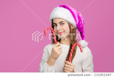 Girl with Christmas Hat Holding Tree-Shaped Candy. Festive girl in purple Santa hat holding Christmas tree Girl with Christmas Hat Holding Tree-Shaped Candy. Festive girl in purple Santa hat holding Christmas tree 131952397