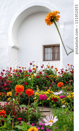 Old red house with geranium flowers blooming in a summer garden Old red house with geranium flowers blooming in a summer garden 131952855