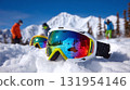Winter sports eyewear reflects mountain views, snowy scenery, and blue skies for outdoor fun.  Other skiers visible in the background. 131954146