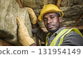 Attic Insulation Install: Focused worker installing fiberglass insulation with safety gear for energy efficiency and temperature control. 131954149