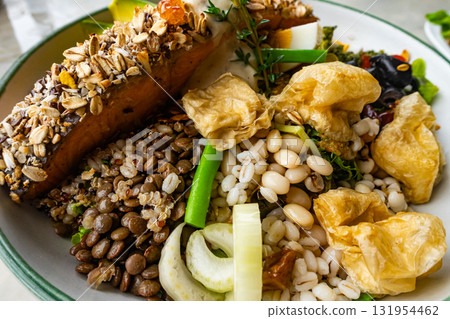 Homemade delicious mixed cereals salad with avocado, green vegetables, olive and roasted salmon steak in white ceramic plate. Homemade delicious mixed cereals salad with avocado, green vegetables, olive and roasted salmon steak in white ceramic plate. 131954462