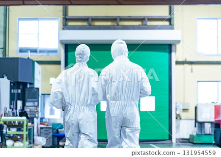 Male and female workers wearing protective clothing walking through a factory Male and female workers wearing protective clothing walking through a factory 131954559