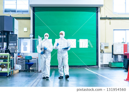 Male and female workers in protective clothing walking through a factory Male and female workers in protective clothing walking through a factory 131954560