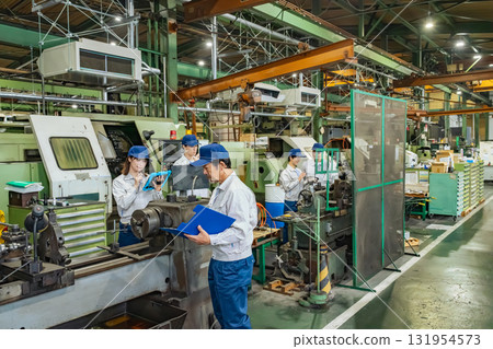 A group of workers operating machine tools in a factory A group of workers operating machine tools in a factory 131954573