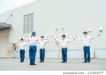 A group of workers doing exercises in front of a factory 131954577