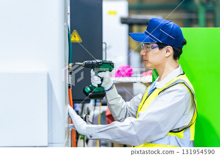 A worker maintaining a machine tool at a factory A worker maintaining a machine tool at a factory 131954590