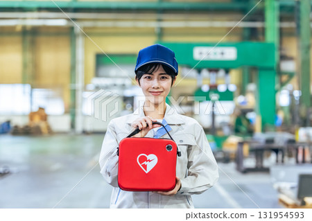 Female worker with AED at factory Female worker with AED at factory 131954593